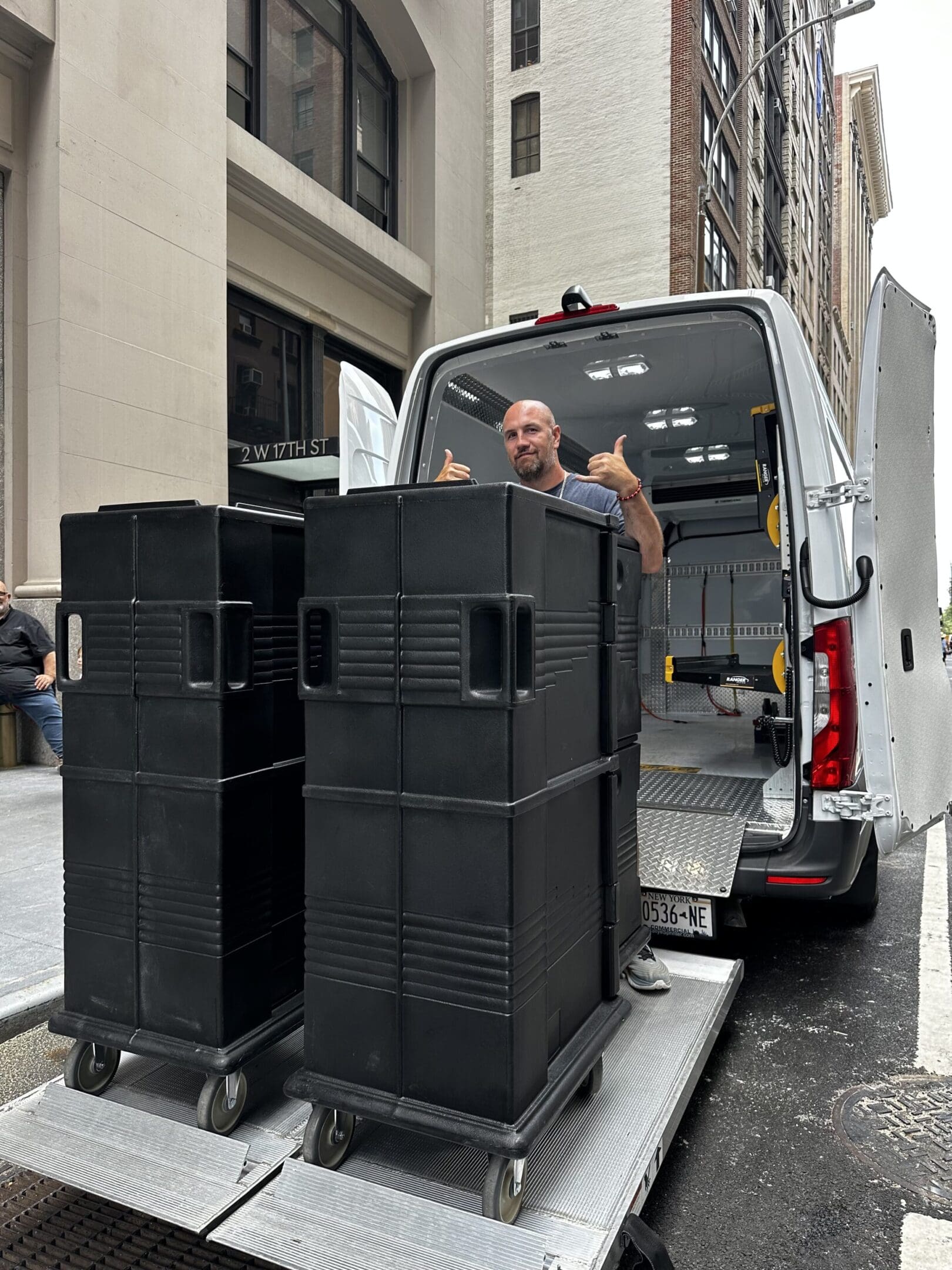 A man in the back of a van with two large speakers.