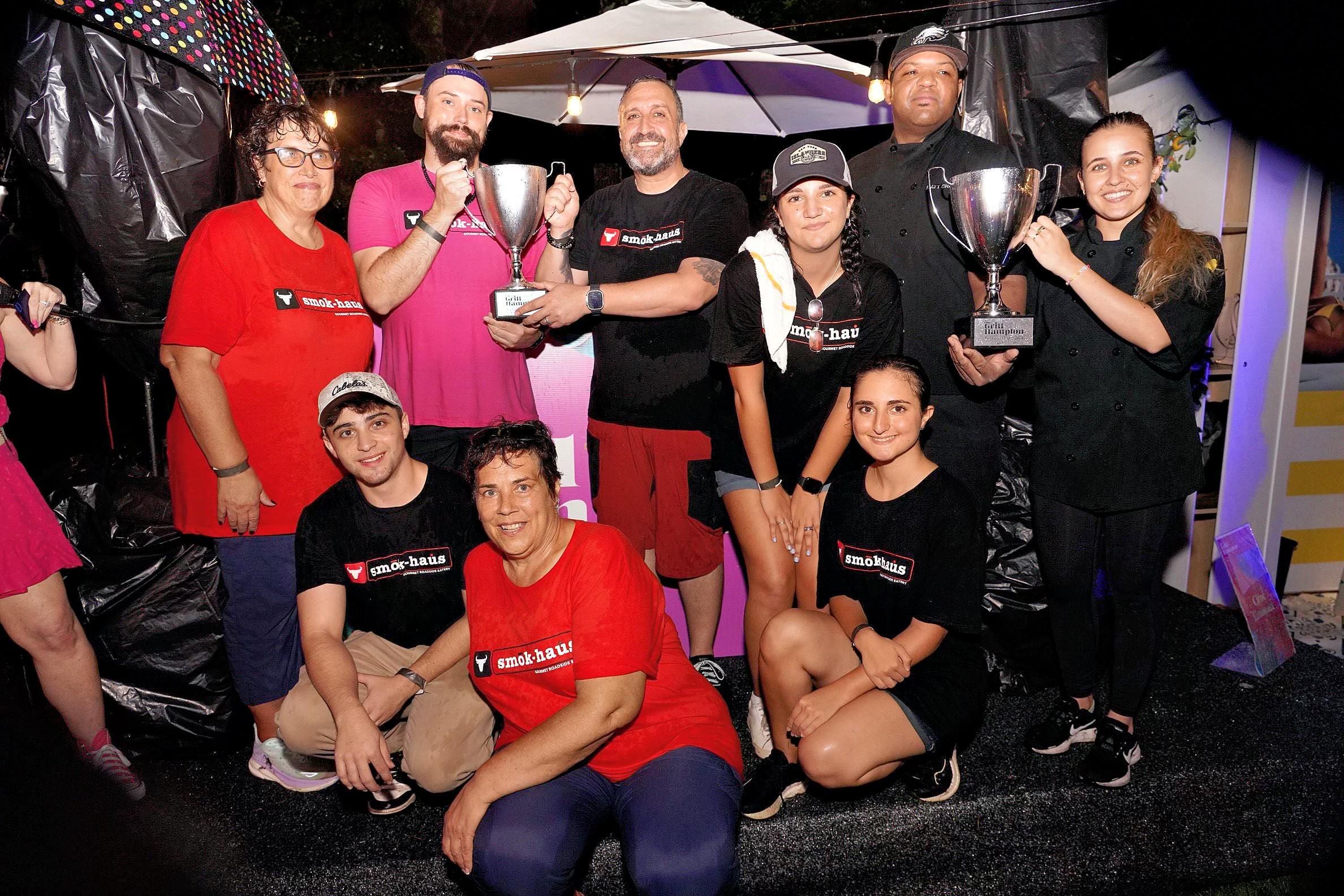 A group of people holding trophies and posing for the camera.