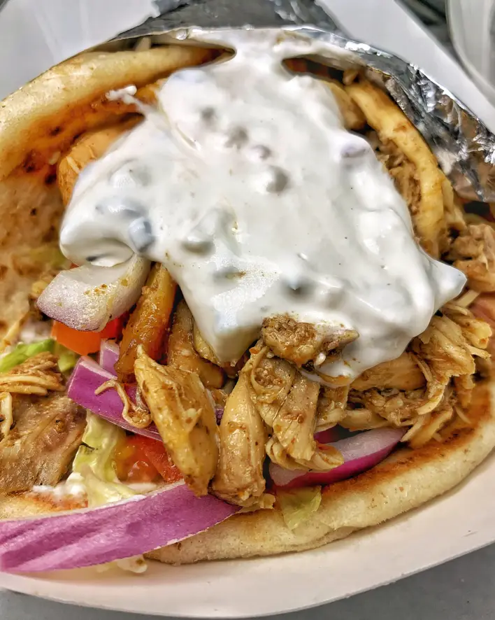 A pita with meat and sauce on top of it.