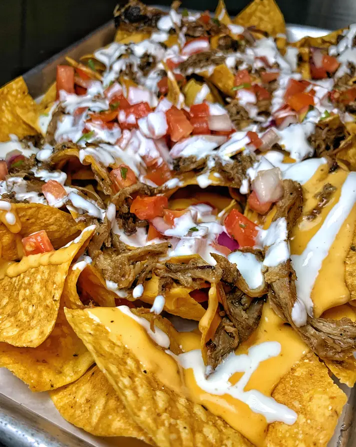 A plate of nachos with cheese and meat.