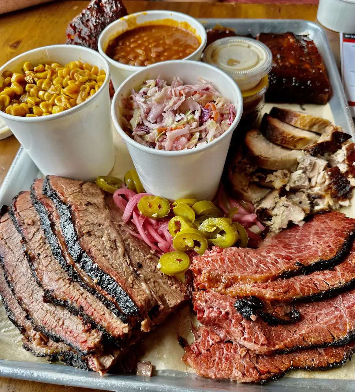 A tray of barbecue meat and sides on top of a table.