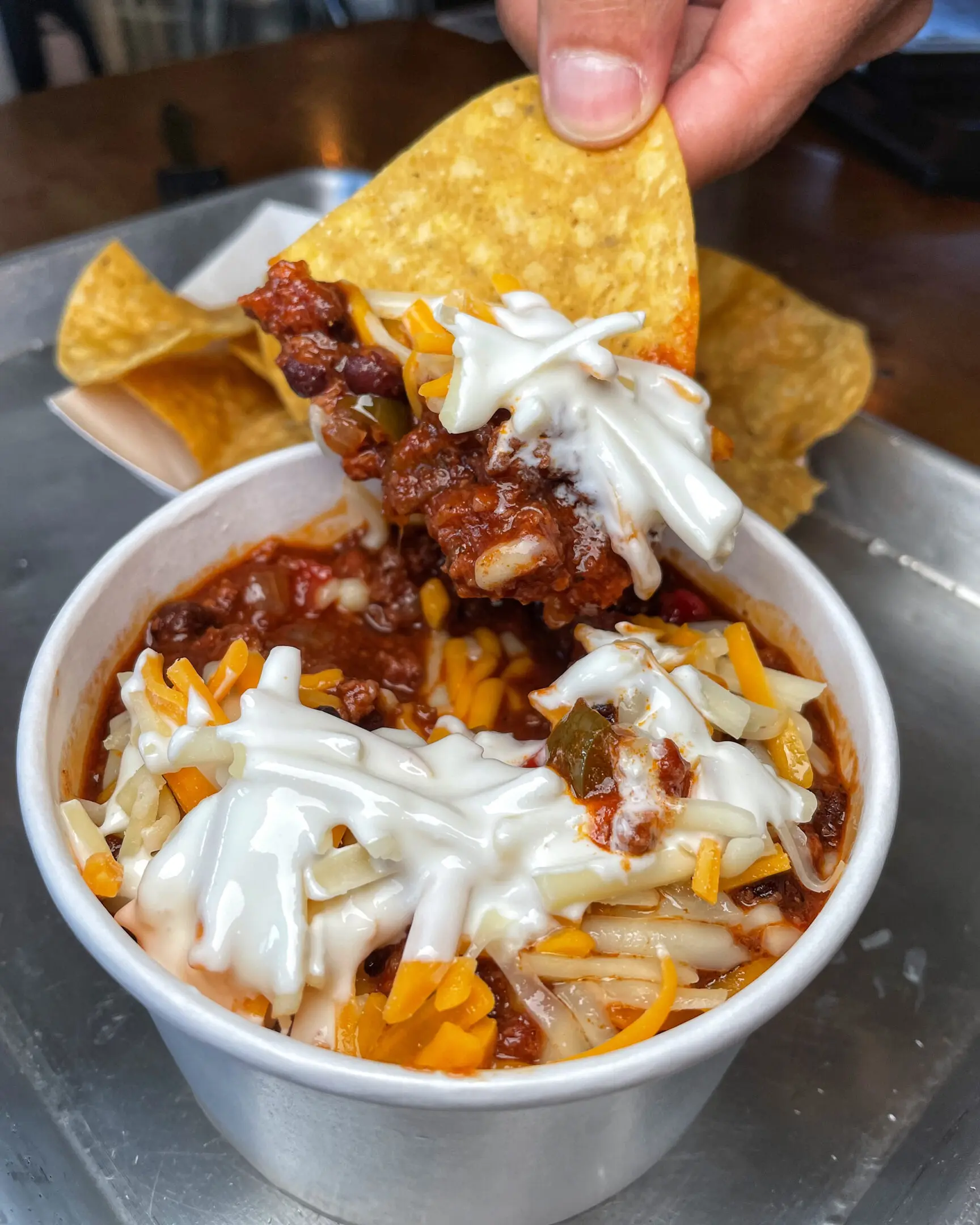 A bowl of chili with cheese and tortilla chips.